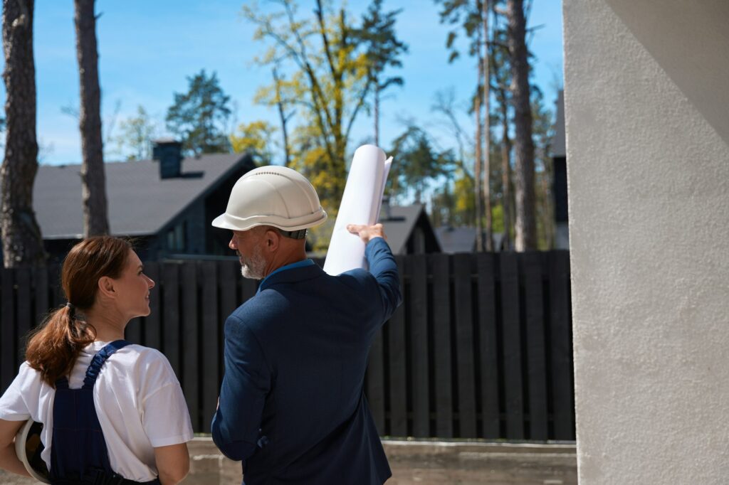 Man cadastral worker holding surveyor map and pointing at construction site